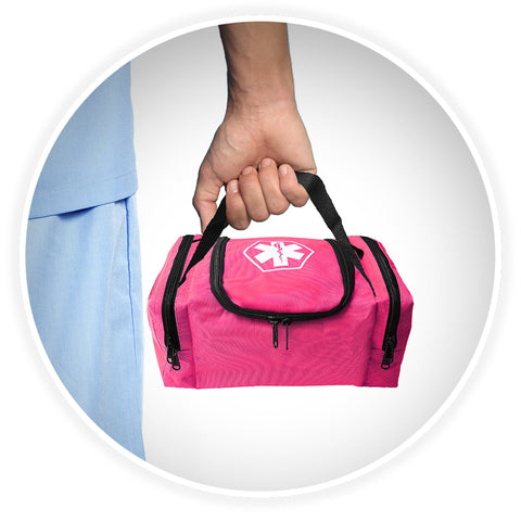 A shot of a person's hand holding the black webbed handle of the pink medical bag, demonstrating its portability against a background of someone wearing blue medical scrubs.
