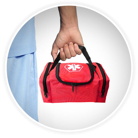 A shot of a person's hand holding the black webbed handle of the red medical bag, demonstrating its portability against a background of someone wearing blue medical scrubs.