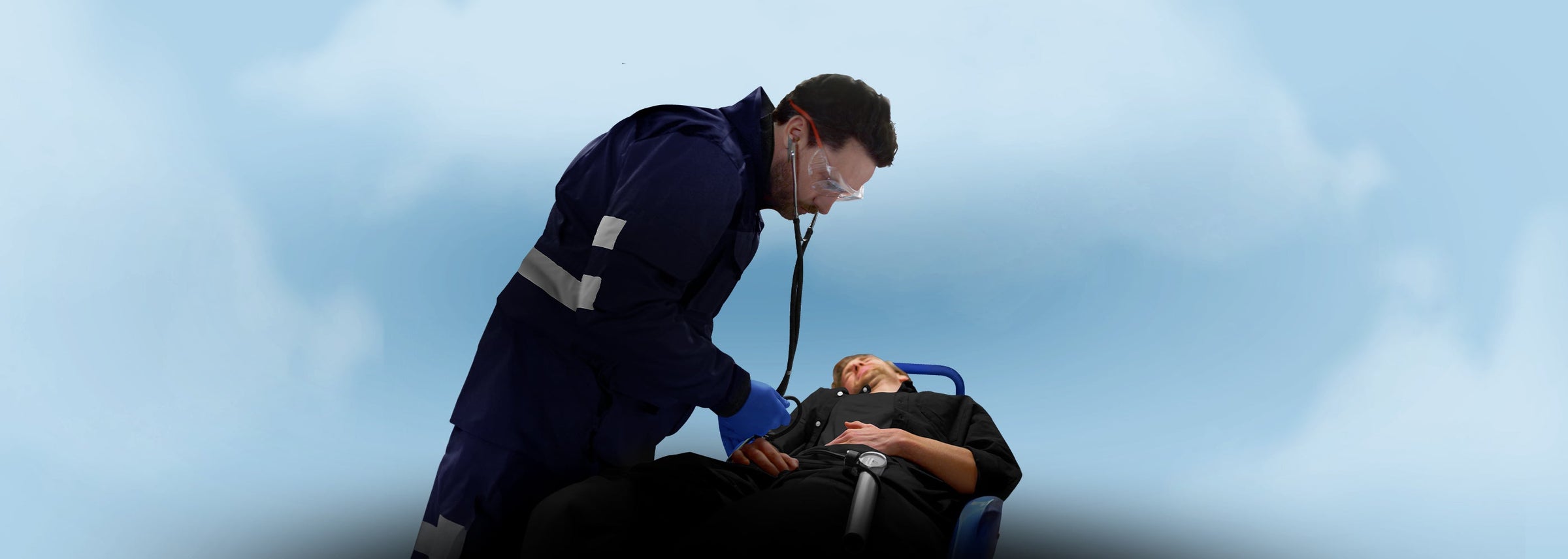 An EMS professional in a navy blue uniform using a stethoscope to examine a patient on a stretcher, representing the EMS Tools & Diagnostic Instruments collection.