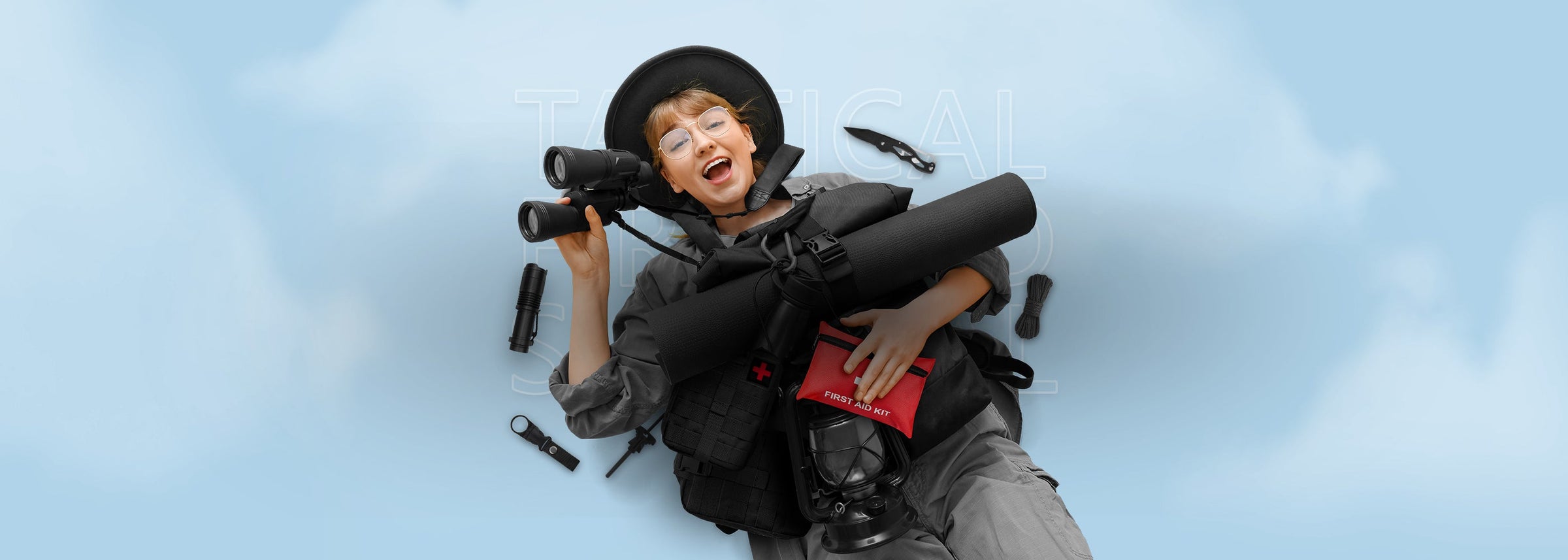 Woman lying down with tactical gear and binoculars, holding a red portable first aid kit, representing the Tactical First Aid & Survival Kit collection.