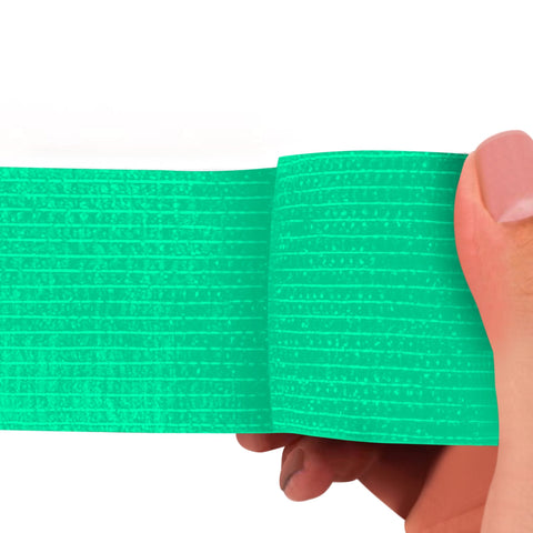 Turquoise adhesive bandage wrap held by a hand on a white background