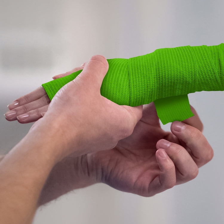 Person applying white bandage to a wrist against a plain background