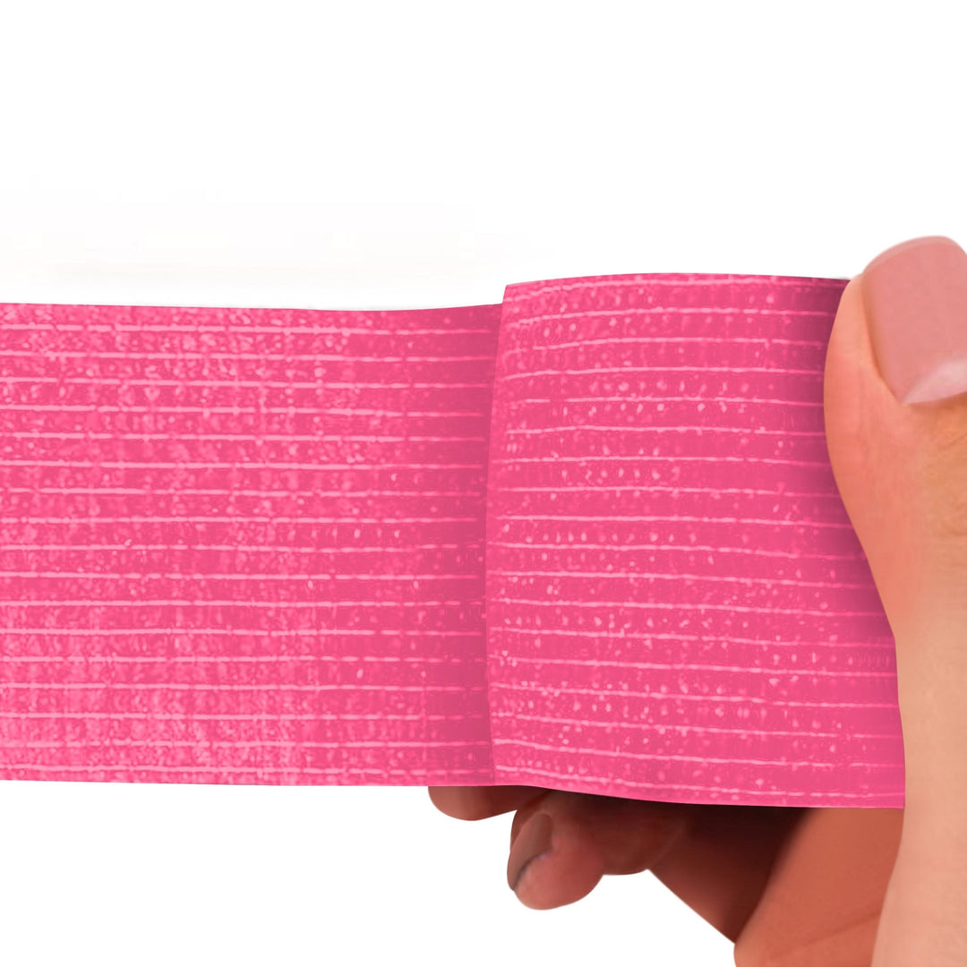 Pink adhesive bandage wrap held by a hand on a white background