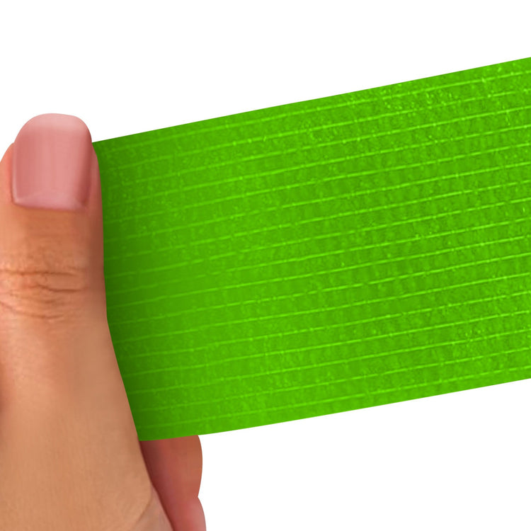 Hand holding a Light green strip of adhesive bandage wrap with a textured pattern on a white background