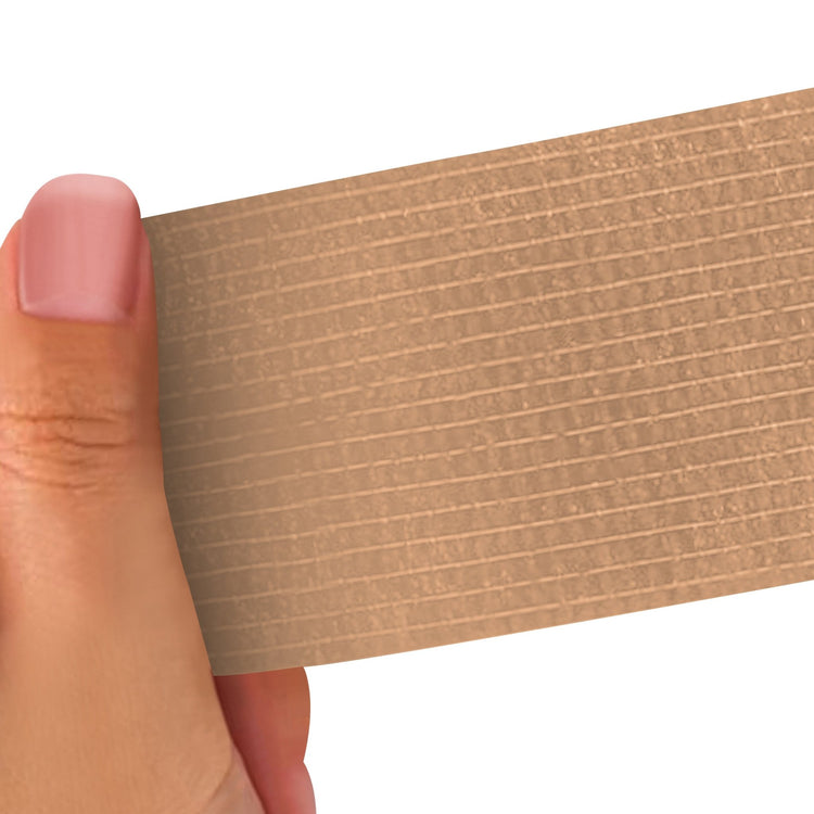 Hand holding a Tan strip of adhesive bandage wrap with a textured pattern on a white background