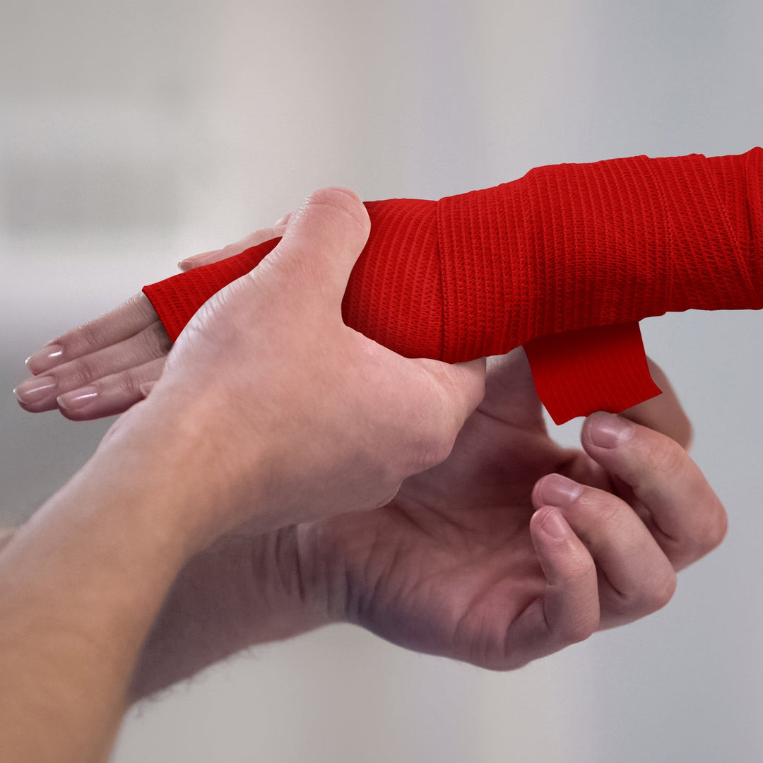 Person applying white bandage to a wrist against a plain background