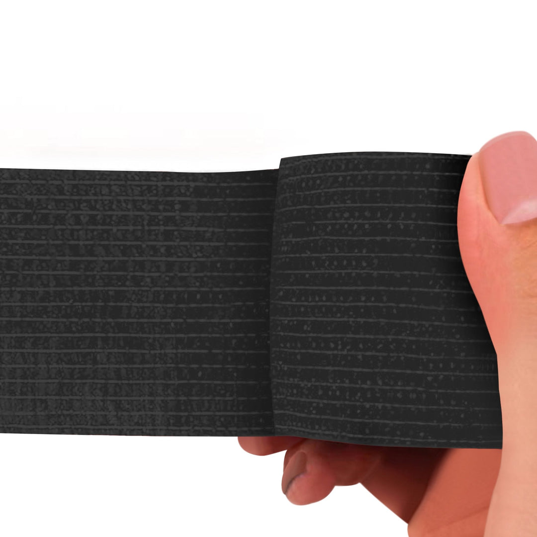 Black adhesive bandage wrap held by a hand on a white background