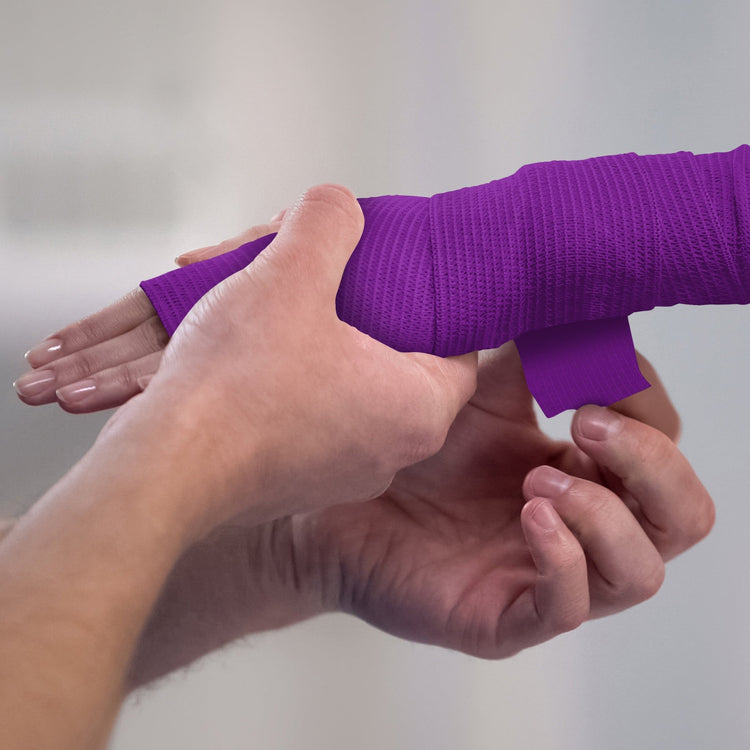 Person applying white bandage to a wrist against a plain background