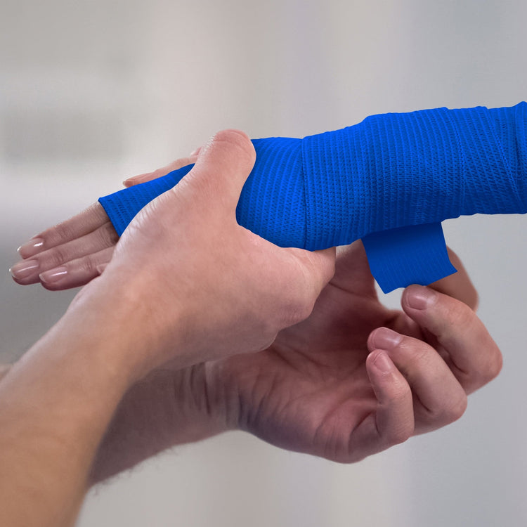 Person applying white bandage to a wrist against a plain background