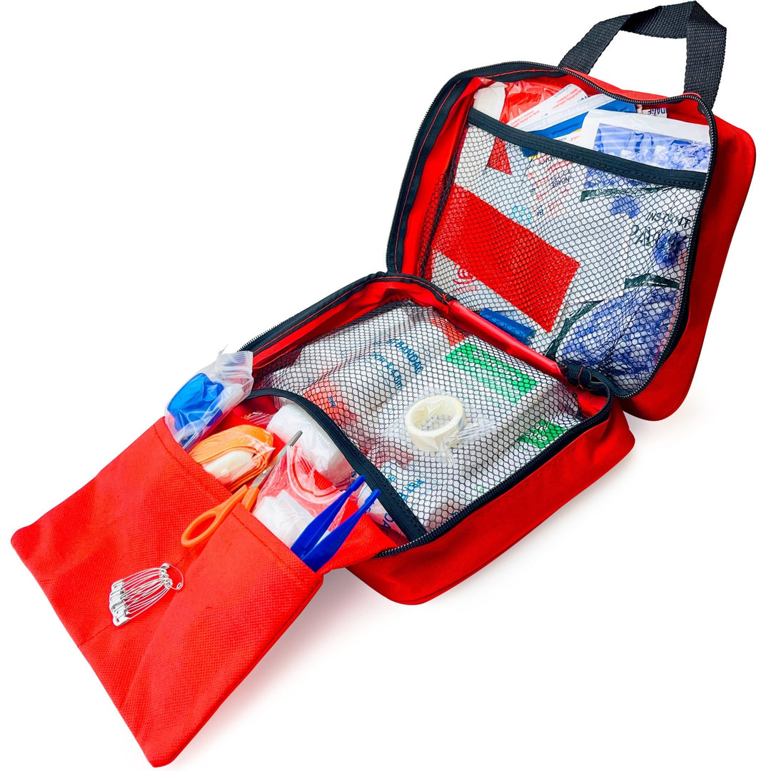 A red first aid bag opened to show its organized interior, featuring mesh pockets, clear vinyl dividers, and various medical supplies like gloves, safety pins, and a CPR mask tucked inside.