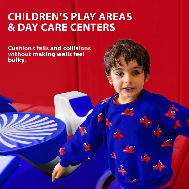 A young boy playing in a colorful indoor area with the walls lined with red safety padding, featuring text that suggests use for "CHILDREN'S PLAY AREAS & DAY CARE CENTERS" to cushion falls.