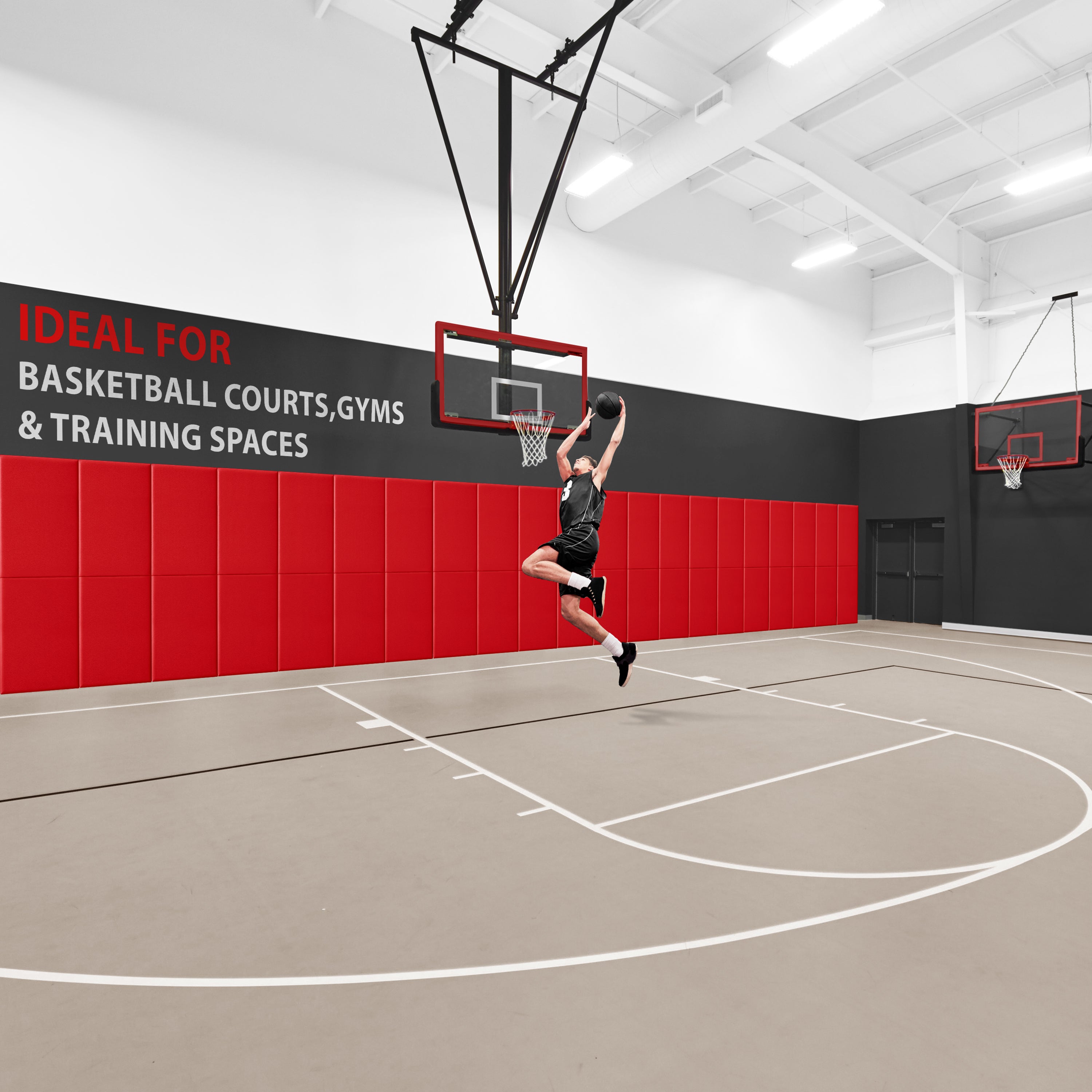 A basketball player jumping to dunk a ball in a gym where the wall behind the hoop is lined with a row of red safety pads, accompanied by text reading "IDEAL FOR BASKETBALL COURTS, GYMS & TRAINING SPACES".