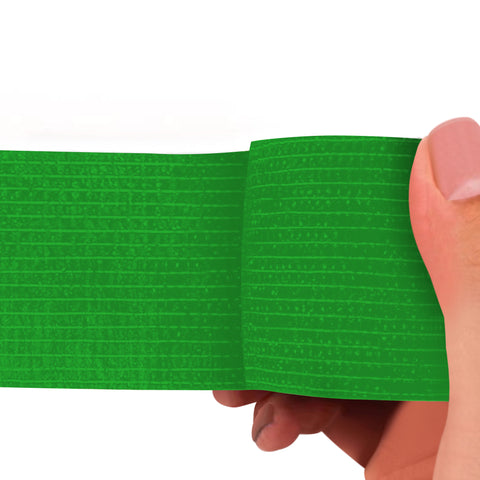 Green adhesive bandage wrap held by a hand on a white background