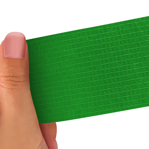Hand holding a green strip of adhesive bandage wrap with a textured pattern on a white background