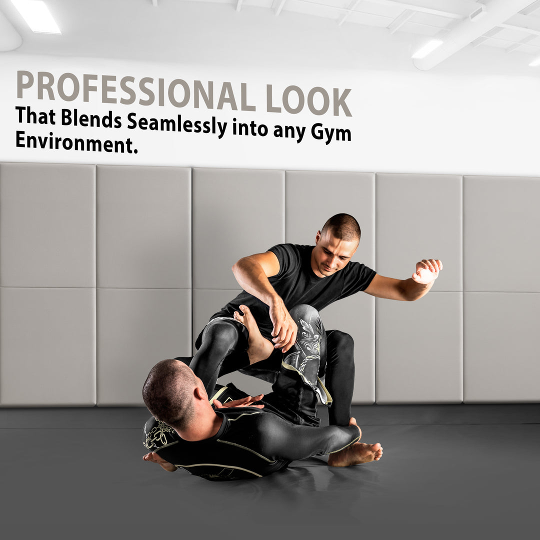 Two athletes grappling on a gym floor with the walls behind them covered in gray protective padding, accompanied by text stating "PROFESSIONAL LOOK That Blends Seamlessly into any Gym Environment".