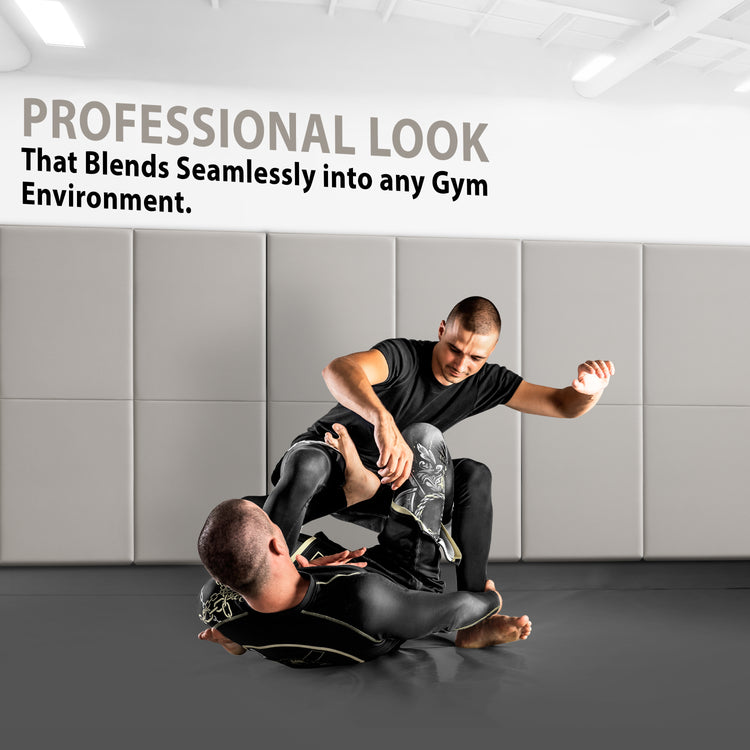 Two athletes grappling on a gym floor with the walls behind them covered in gray protective padding, accompanied by text stating "PROFESSIONAL LOOK That Blends Seamlessly into any Gym Environment".