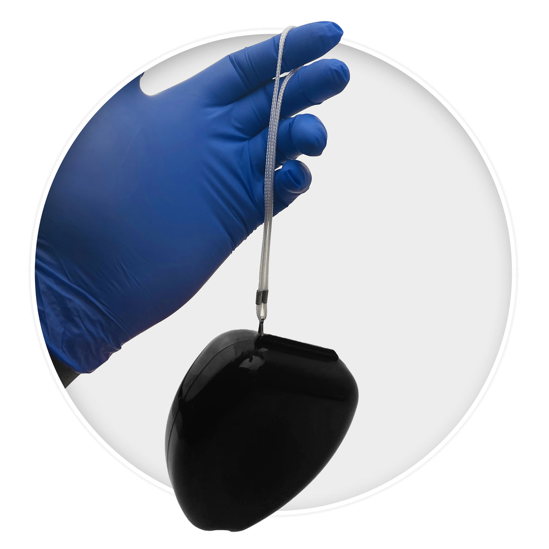 A hand wearing a blue nitrile glove holding a black CPR mask case suspended by its white wrist strap.
