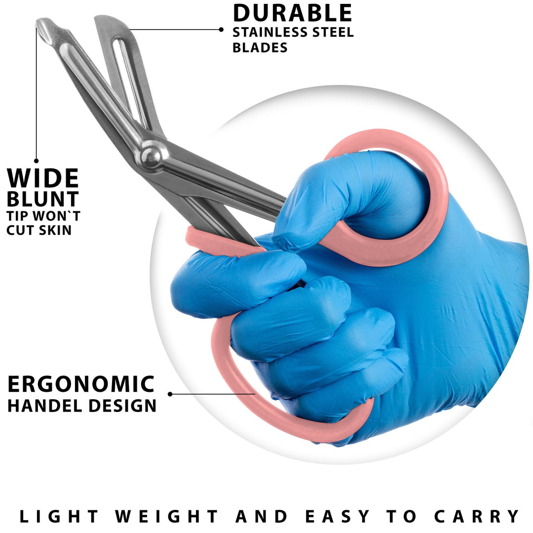 A close-up action shot of a hand in a blue medical glove holding the pink trauma shears. Text highlights the "Wide Blunt Tip" designed so it won't cut skin, the ergonomic handle design, and durable stainless steel blades.