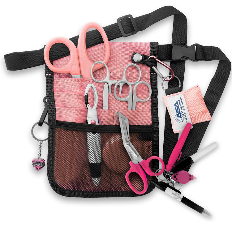 A fully assembled pink nursing organizer pouch attached to a black adjustable waist strap. The pouch is filled with medical supplies, including pink-handled trauma shears, hemostats, a CPR face shield keychain, a retractable tape measure, and various writing instruments. A decorative pink heart charm hangs from the side.