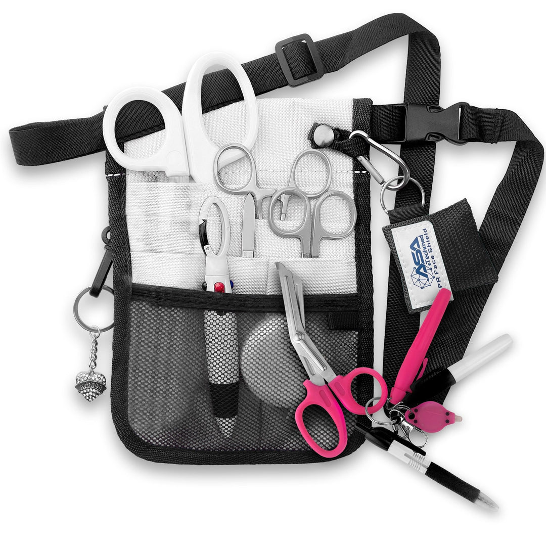 A fully assembled silver nursing organizer pouch attached to a black adjustable waist strap. The pouch is filled with medical supplies, including white-handled trauma shears, hemostats, a CPR face shield keychain, a retractable tape measure, and various writing instruments. A decorative silver heart charm hangs from the side.