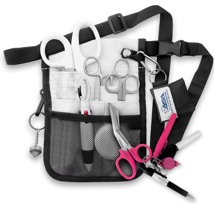 A fully assembled silver nursing organizer pouch attached to a black adjustable waist strap. The pouch is filled with medical supplies, including white-handled trauma shears, hemostats, a CPR face shield keychain, a retractable tape measure, and various writing instruments. A decorative silver heart charm hangs from the side.