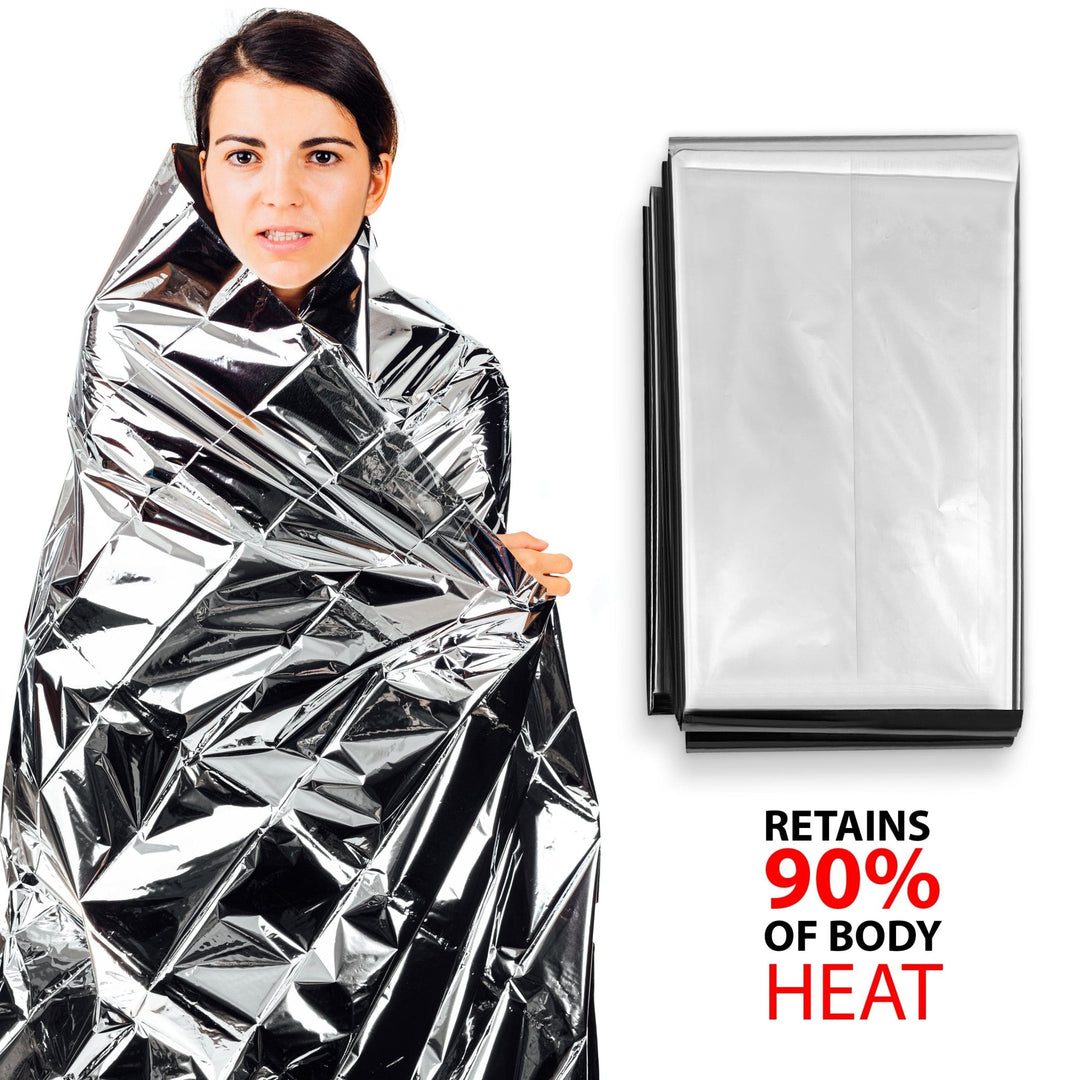 A woman standing wrapped in a silver foil thermal emergency blanket next to a neat, folded package of the same blanket. Large text on the right reads "Retains 90% of Body Heat."