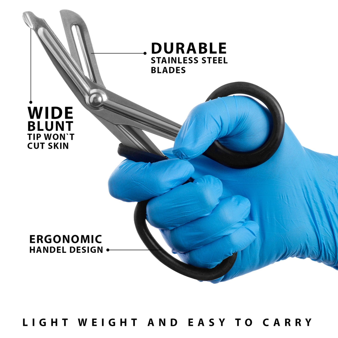 A close-up of a hand in a blue medical glove holding stainless steel trauma shears. Text annotations highlight features including "durable stainless steel blades," a "wide blunt tip" that won't cut skin, and an "ergonomic handle design."
