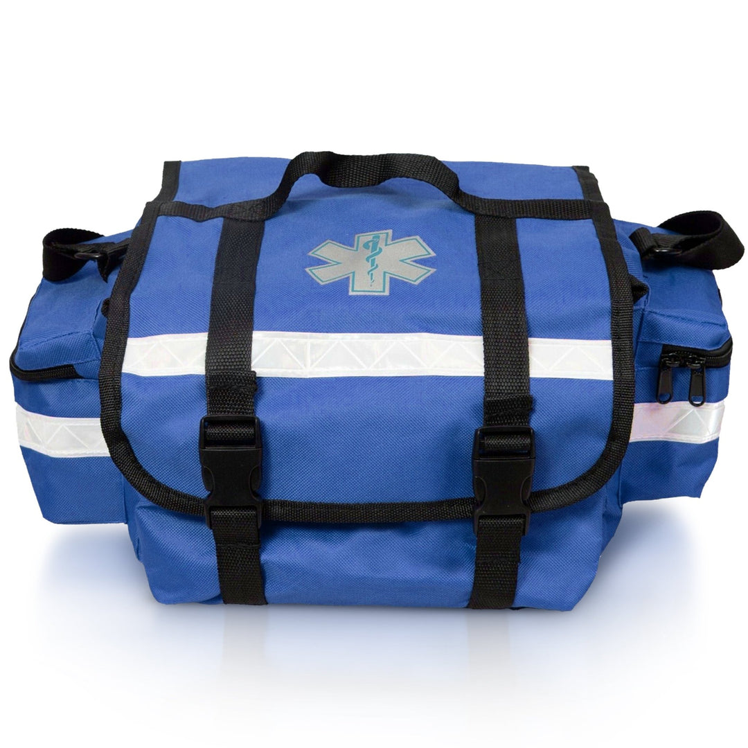A straight-on front view of the blue EMT trauma bag. It features a central Star of Life symbol, two black straps with buckles securing the top flap, and a prominent reflective strip running horizontally across the front.