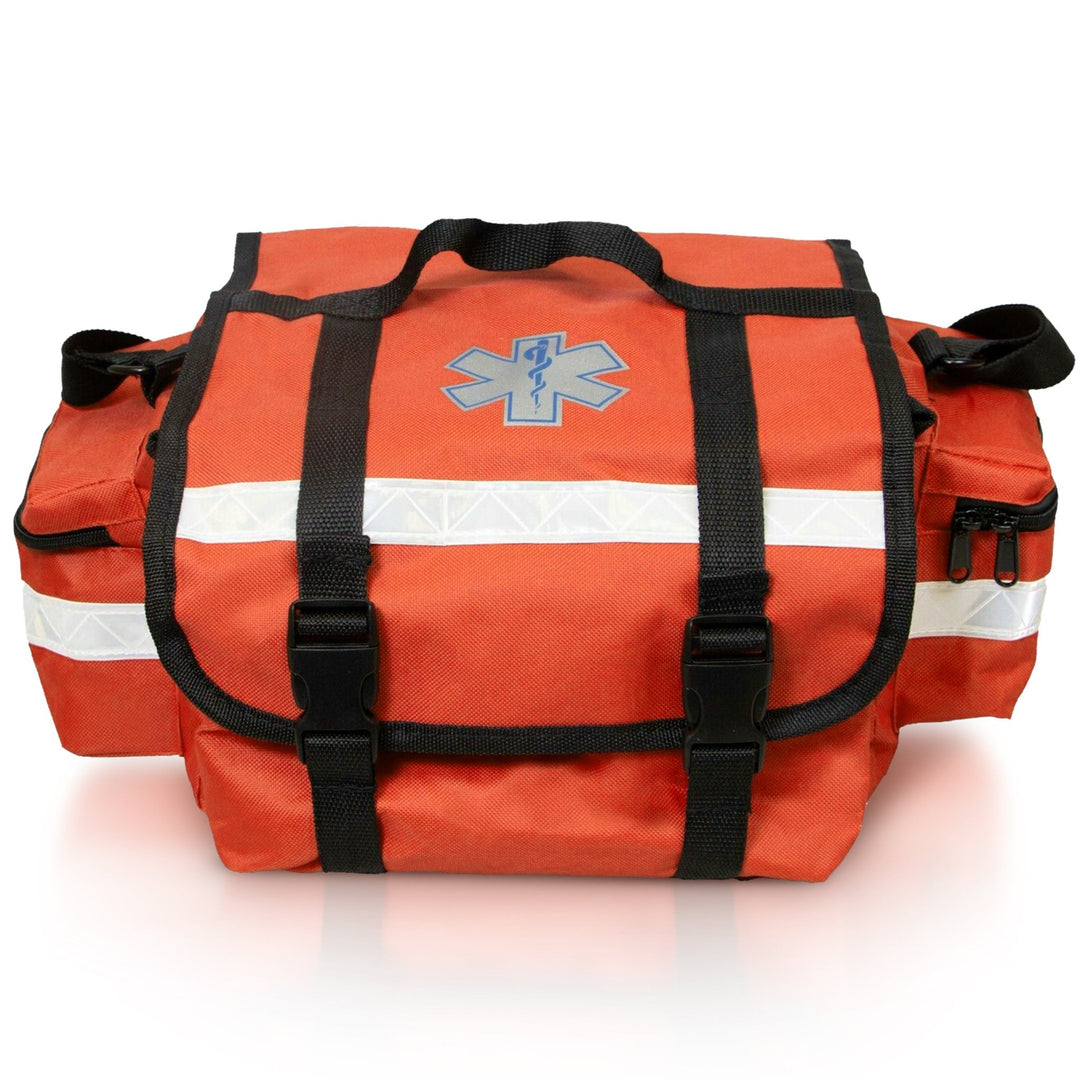 A straight-on front view of the orange EMT trauma bag. It features a central Star of Life symbol, two black straps with buckles securing the top flap, and a prominent reflective strip running horizontally across the front.