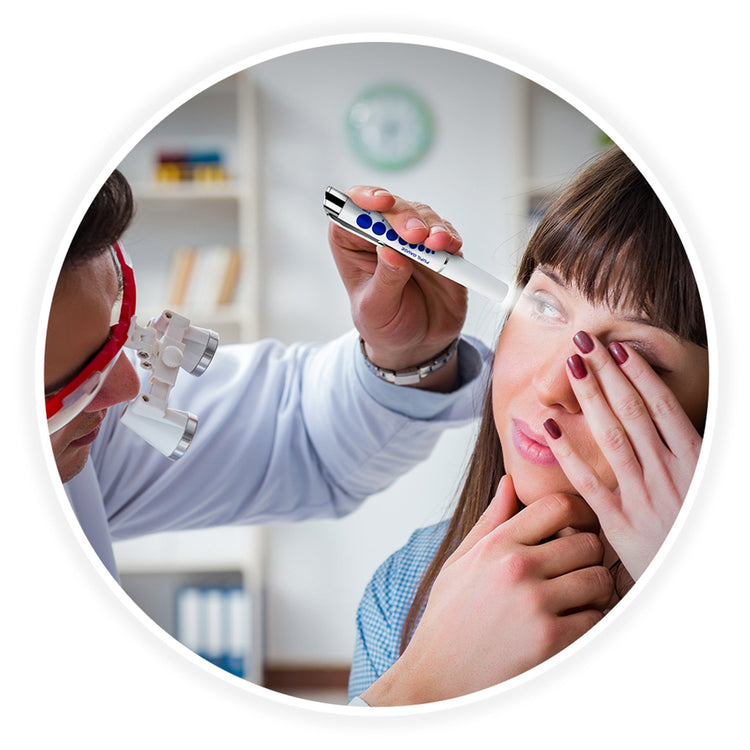A circular frame showing a medical professional wearing magnifying loupes using the white pen light to examine a female patient's eye while she covers her other eye with her hand.