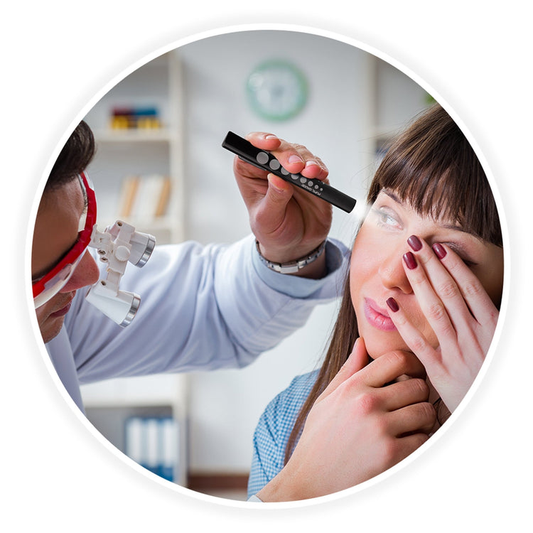 A circular frame showing a medical professional wearing magnifying loupes using the black pen light to examine a female patient's eye while she covers her other eye with her hand.
