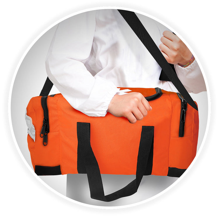 A person wearing a white medical coat carries the orange trauma bag over their shoulder using the adjustable black strap.