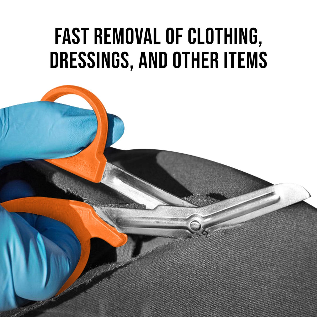 A pair of orange shears held by blue-gloved hands cutting through thick black fabric. Text above reads, "FAST REMOVAL OF CLOTHING, DRESSINGS, AND OTHER ITEMS".