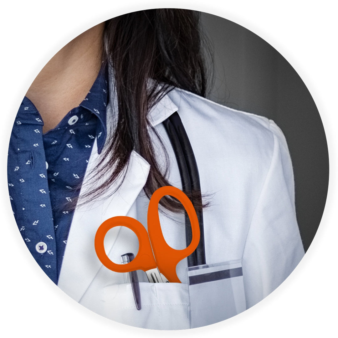 A close-up lifestyle image showing a medical professional in a white coat with a stethoscope, featuring orange trauma shears tucked into their chest pocket.