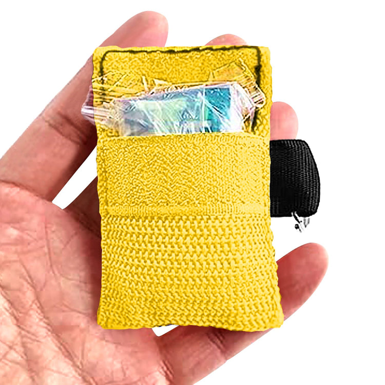 A hand holding an open yellow CPR face shield keychain pouch, revealing a clear plastic packet containing a face shield and gloves stored inside the front velcro pocket.
