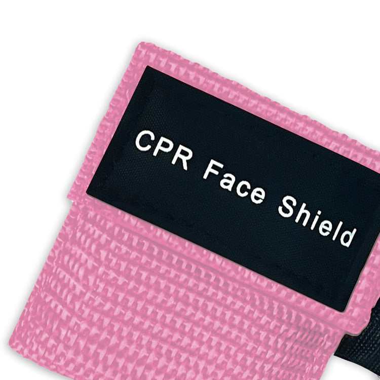 A top-down close-up view of a single pink CPR keychain pouch, highlighting the woven fabric texture and the black identification label.