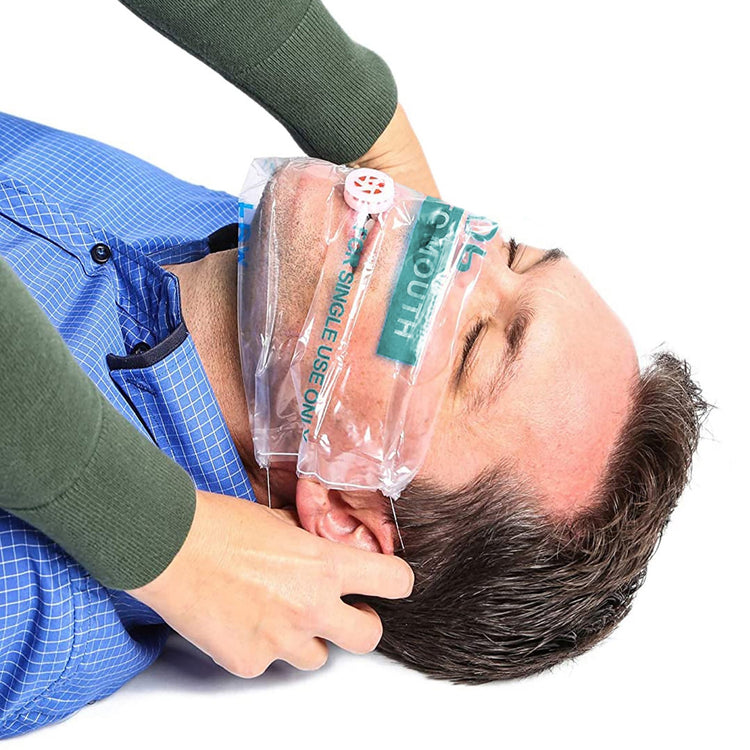 A demonstration of a first aid scenario where a person is applying a clear CPR face shield over a patient's face to prepare for rescue breathing.