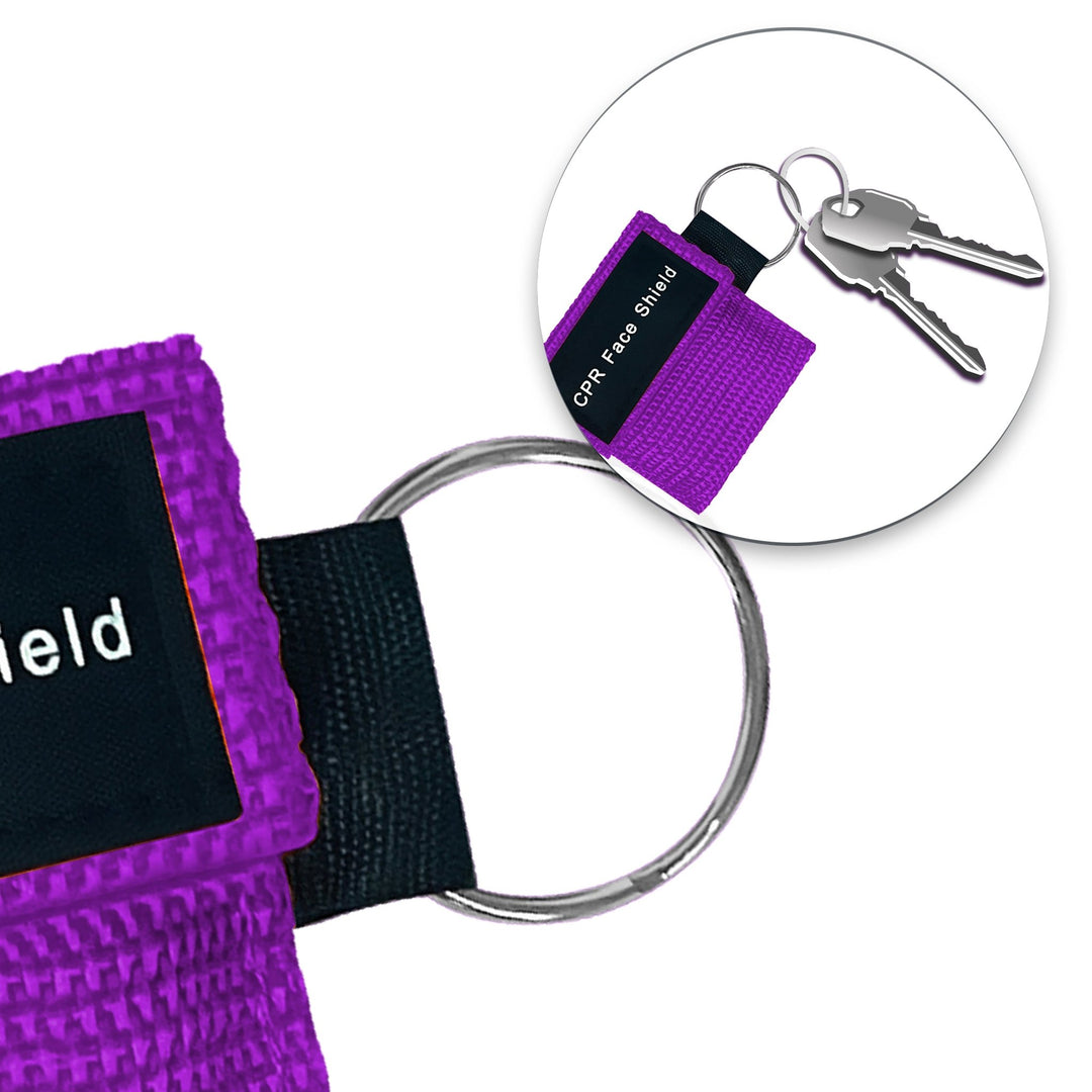 A lifestyle close-up showing a purple CPR face shield pouch attached to a set of car keys, demonstrating its compact size and portability for everyday carry.