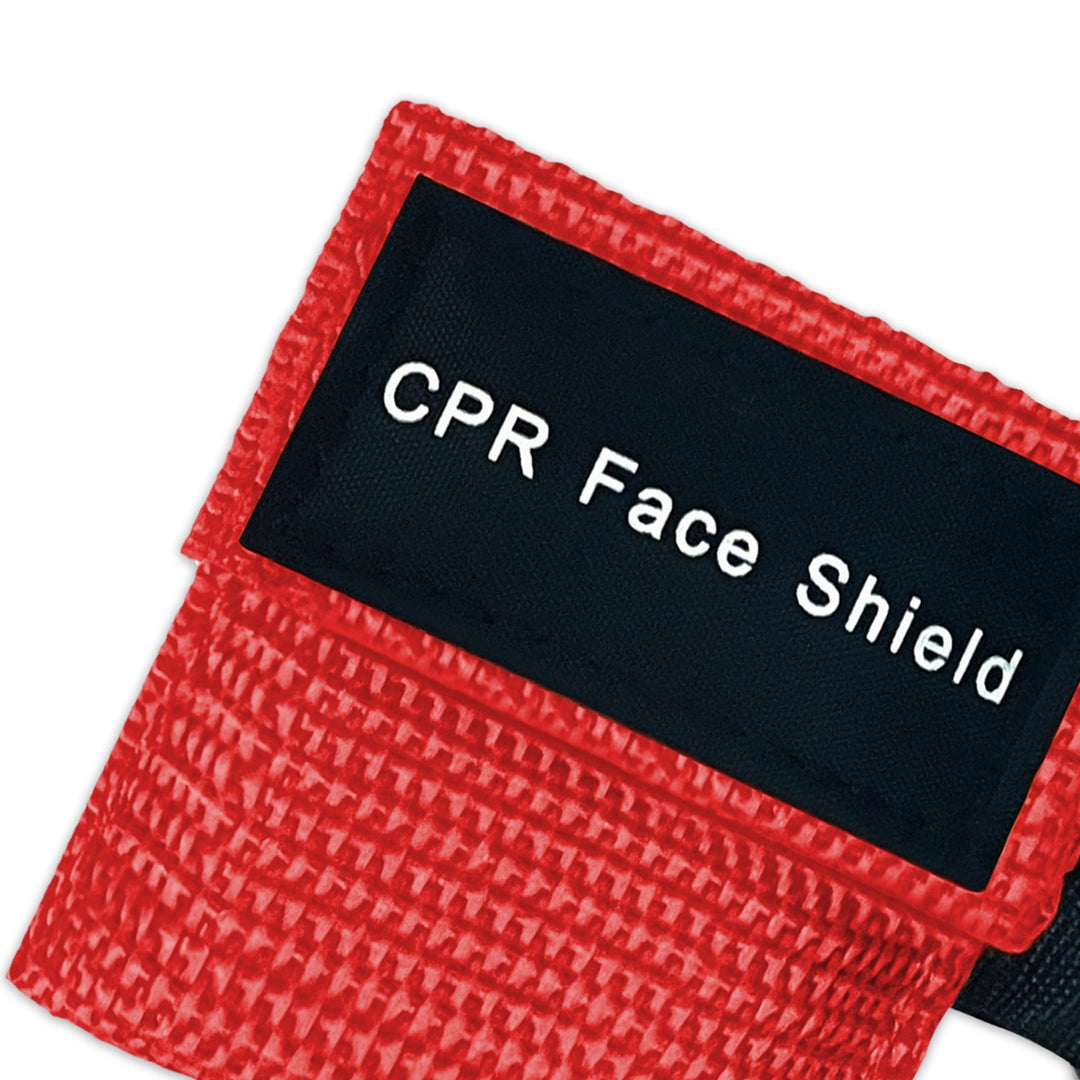 A top-down close-up view of a single red CPR keychain pouch, highlighting the woven fabric texture and the black identification label.