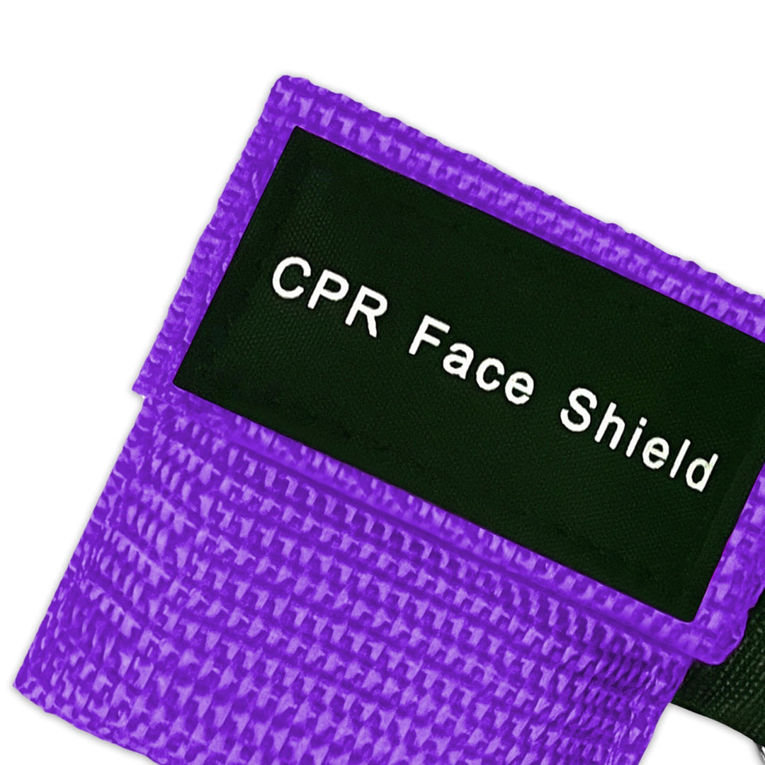 A top-down close-up view of a single purple CPR keychain pouch, highlighting the woven fabric texture and the black identification label.