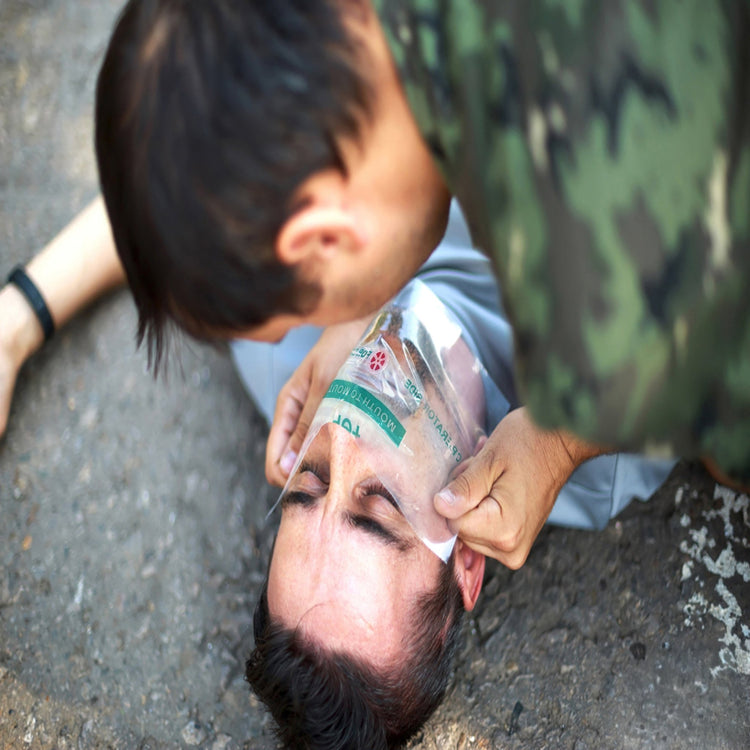 A close-up usage image showing a rescuer applying a CPR face shield to a person wearing military camouflage, ensuring a safe barrier for emergency resuscitation.