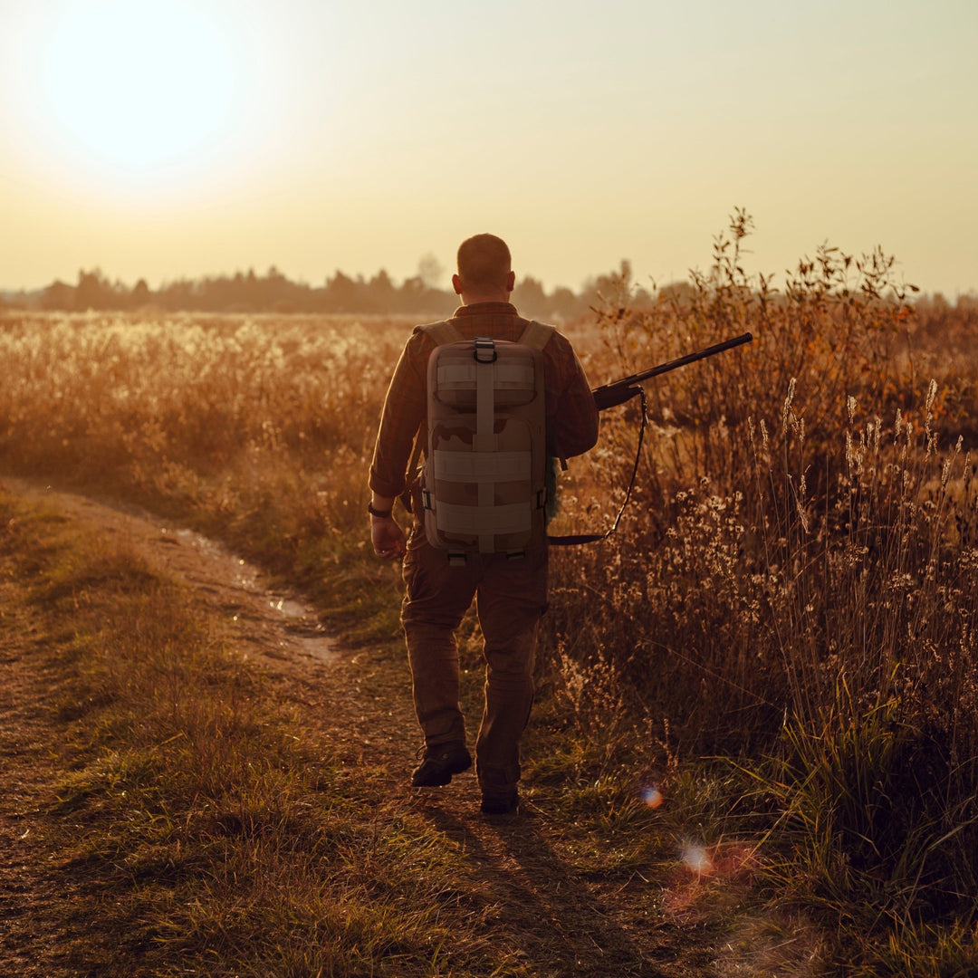 A man carrying the tactical backpack while walking through a field, illustrating its suitability for hiking, travel, and outdoor activities.