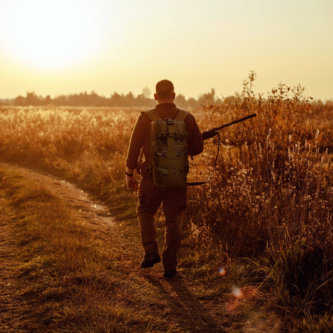 A man carrying the tactical backpack while walking through a field, illustrating its suitability for hiking, travel, and outdoor activities.