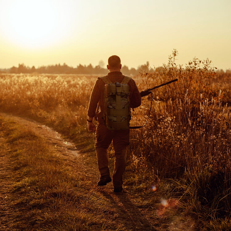 A man carrying the tactical backpack while walking through a field, illustrating its suitability for hiking, travel, and outdoor activities.