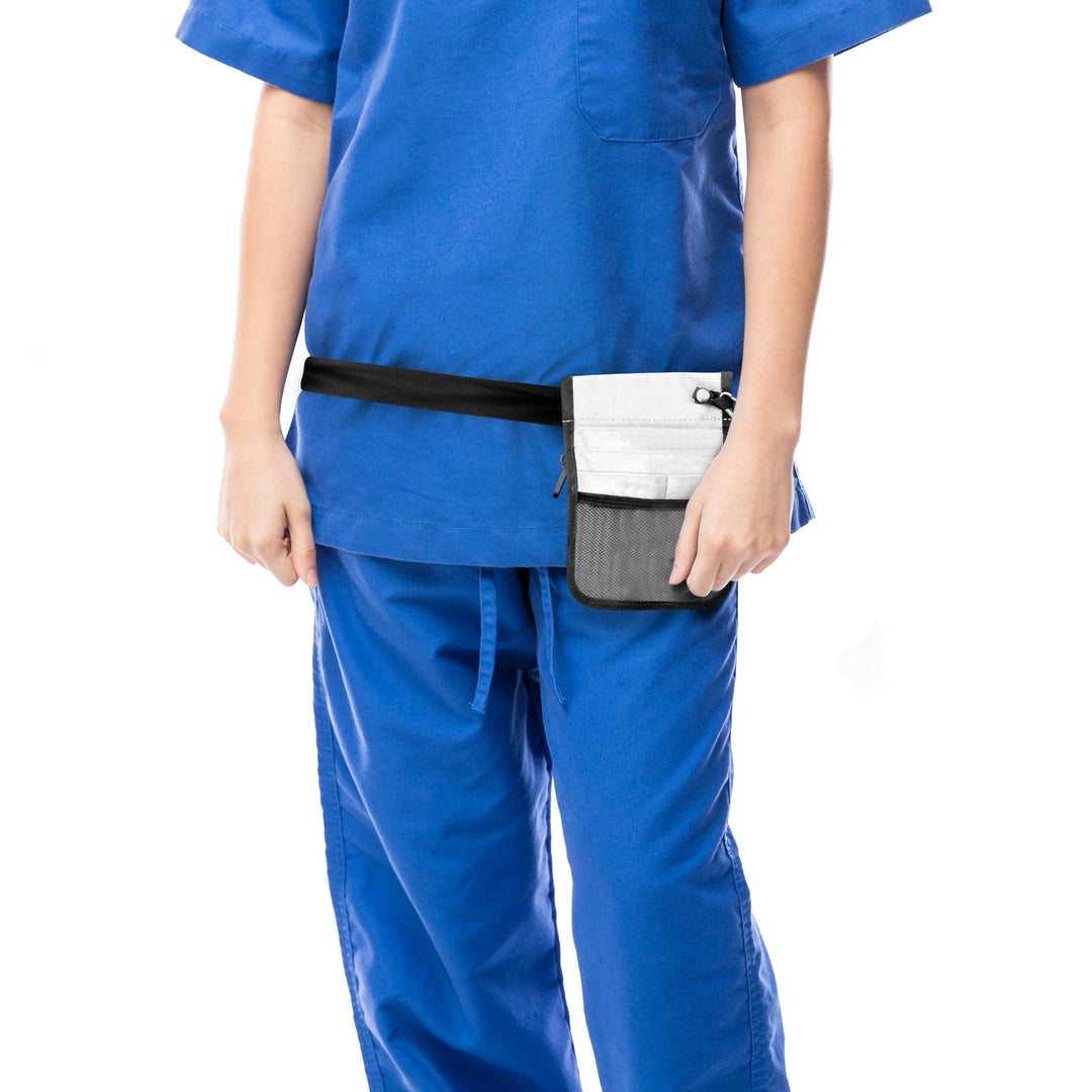 A cropped lifestyle shot focusing on the utility of the bag. A nurse in blue scrubs is shown from the torso down, wearing the white medical organizer belt around her hips. The bag sits flat against the body, demonstrating its slim profile.