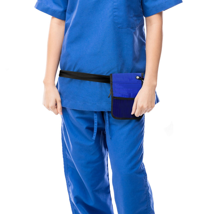 A cropped lifestyle shot focusing on the utility of the bag. A nurse in blue scrubs is shown from the torso down, wearing the blue medical organizer belt around her hips. The bag sits flat against the body, demonstrating its slim profile.