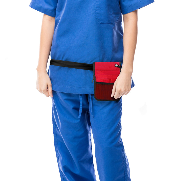 A cropped lifestyle shot focusing on the utility of the bag. A nurse in blue scrubs is shown from the torso down, wearing the red medical organizer belt around her hips. The bag sits flat against the body, demonstrating its slim profile.