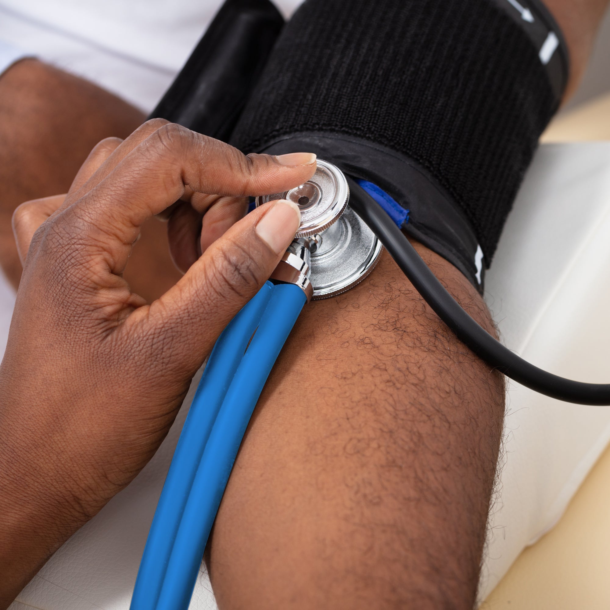 A close-up lifestyle image of a medical professional using the sea breeze dual-head stethoscope to monitor a patient's blood pressure. The stethoscope chest piece is held firmly against the patient's arm just below a black blood pressure cuff.