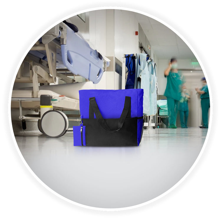 The blue medical utility tote bag placed on a hospital floor with a blurred background of a busy clinical hallway and gurneys.