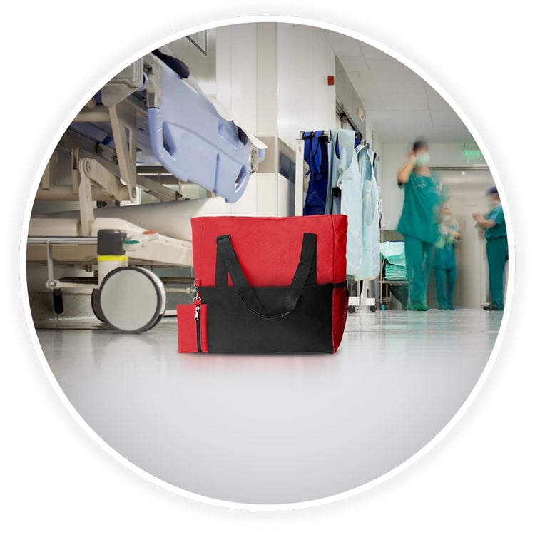 The red medical utility tote bag placed on a hospital floor with a blurred background of a busy clinical hallway and gurneys.